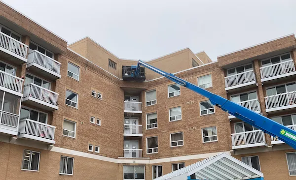 Worker caulking a window using a boom lift